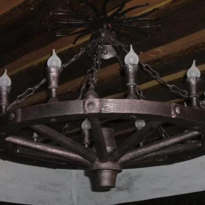 Wielopunktowa lampa wisząca w formie koła od wozu lub bryczki. Metaloplastyka stylizowana na drewno idealna do karczm, wnętrz myśliwskich, rancza i stajni.