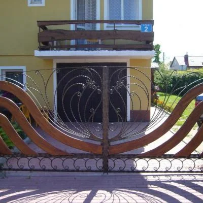 Ekskluzywna brama skrzydłowa łącząca drewno i artystyczną metaloplastykę,  unikatowe ogrodzenie posiadłości.