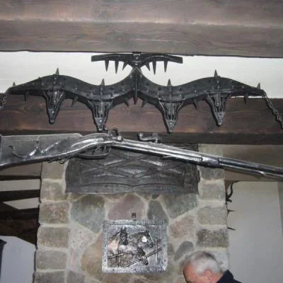 Monumentalna lampa wisząca z autorską repliką muszkietu, rzeźbiarska konstrukcja w barwie palonego metalu na łańcuchach do wnętrz rustykalnych