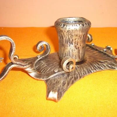 Artystyczny świecznik z centralnym osadzeniem świecy w stylu vintage, bogato fakturowana ozdobna metalowa patyna. 
