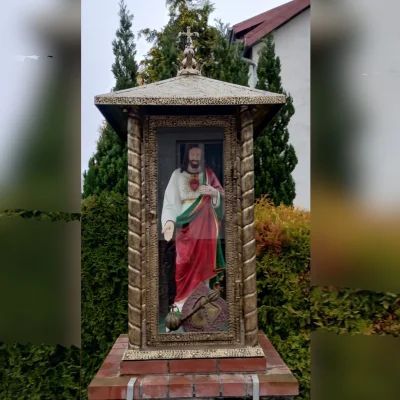 Wolnostojąca kapliczka przydrożna  o strukturze gabloty. Zamykana metalowa architektura sakralna dedykowana do bezpiecznej ekspozycji figur świętych.