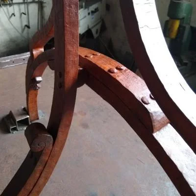 Nitowany detal bocznej sekcji artystycznego stojaka rowerowego wykonany z pełnej stali 20 × 30 mm z kutymi wolutami, naturalną patyną i tradycyjnymi połączeniami nitowanymi na gorąco.