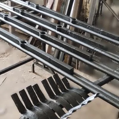 Komplet zrekonstruowanych elementów zabytkowej balustrady z żelaza pudlarskiego przygotowanych do ponownego montażu przy historycznej mogile.