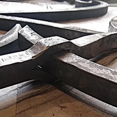 Przebijanie pręta stalowego na gorąco – tradycyjna technika kowalska stosowana w detalach architektury zabytkowej, element kutego emblematu historycznego budynku podczas renowacji
